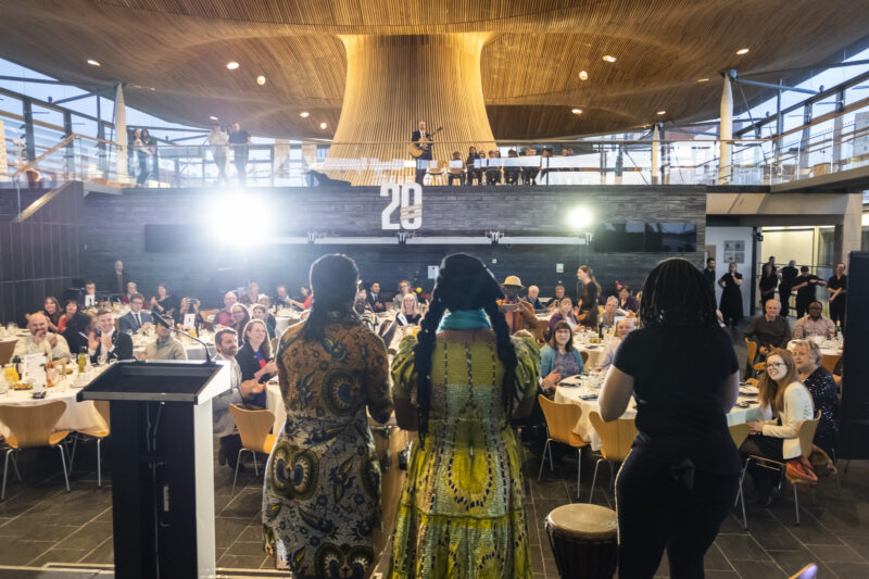 Image of an event in 2019 at the Senedd. It shows Love Zimbabwe band playing on a stage in front of a crowd .